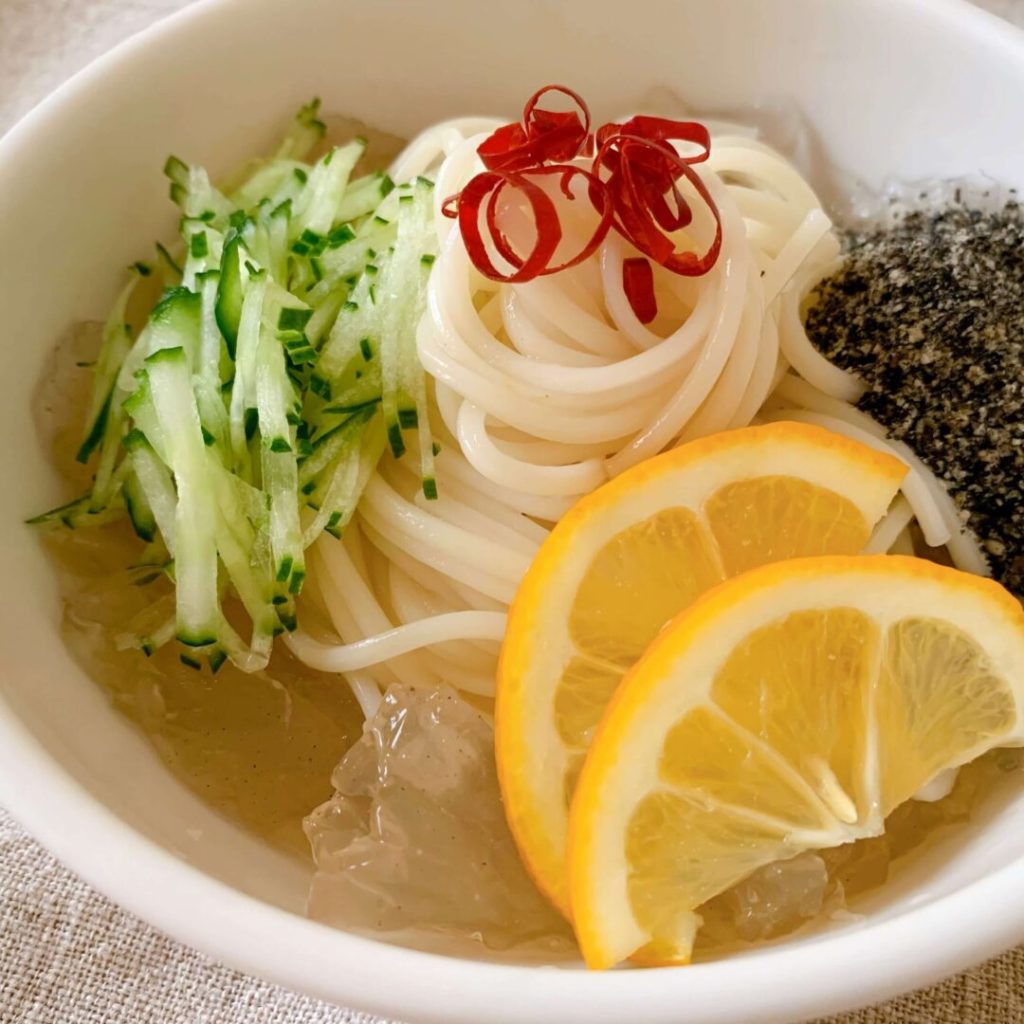 レモンときゅうりと黒ゴマが添えられたそうめん